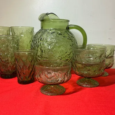 Mid-century green textured glassware set, including a large pitcher, tall tumblers, small drinking glasses, and stemmed dessert dishes...