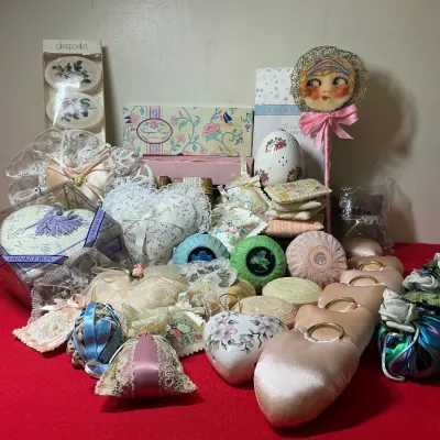 Collection of vintage bath items and sachets, including specialty boxed soaps, lace-trimmed cushions, ceramic pomanders, and satin heart...