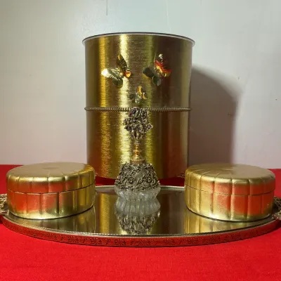 Vintage Hollywood Regency vanity set, featuring a gold-toned textured trash can decorated with butterflies, a mirrored tray with ornate...
