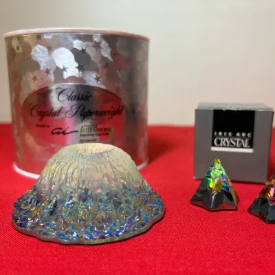 Iridescent glass volcano-shaped paperweight alongside two Iris Arc crystal pyramid figurines with original boxes.