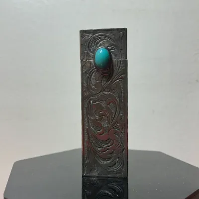 Vintage Southwestern-style silver cigarette lighter featuring detailed floral engraving and a faux turquoise cabochon inset.
