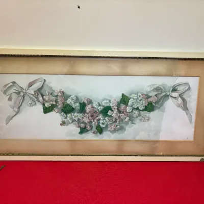 Antique framed floral print depicting a garland of pink and white blossoms tied with ribbon bows, housed in a cream-colored frame with...