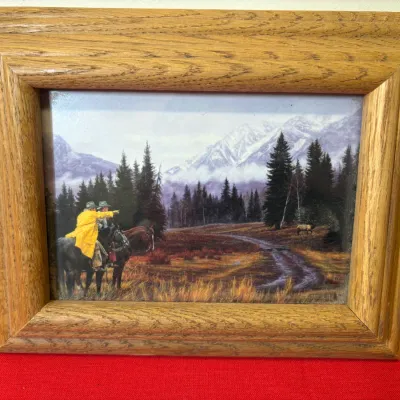Framed Western landscape art print depicting horseback riders in a mountainous landscape, housed in a thick natural oak wood frame.