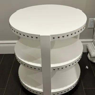 Sale Photo Thumbnail #6: Contemporary round white painted end table featuring three tier shelves trimmed with silver nailhead studs.