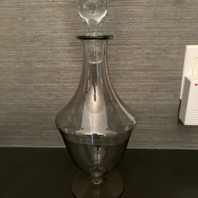 Sale Photo Thumbnail #72: Smokey grey glass decanter with a matching teardrop glass stopper, featuring a pedestal base and flared body.