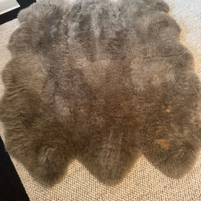 Sale Photo Thumbnail #59: Large taupe sheepskin area rug featuring a natural freeform shape, showing minor surface discoloration on one side.