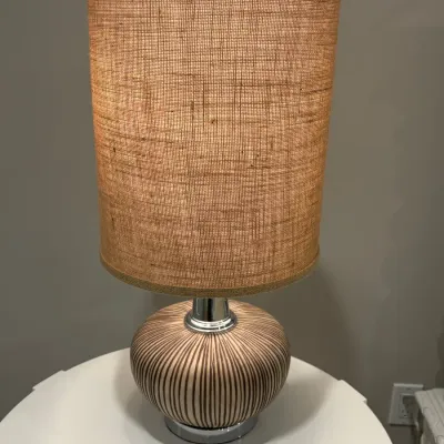 Sale Photo Thumbnail #17: Modern table lamp featuring a ribbed ceramic base with dark vertical stripes and a tall cylindrical burlap drum shade.