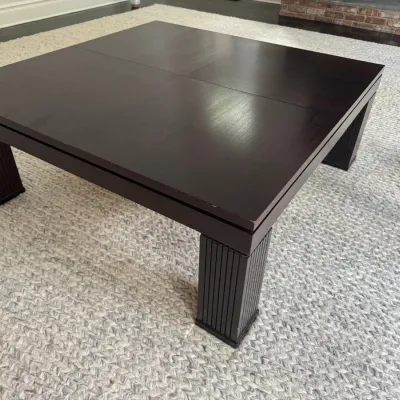 Sale Photo Thumbnail #40: Large dark-stained square wooden coffee table featuring fluted columnar legs and minor surface wear along the edges.