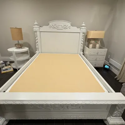Sale Photo Thumbnail #16: Ornate white painted wooden bed frame featuring detailed scrollwork carvings on the headboard and footboard, flanked by matching white nightstands.