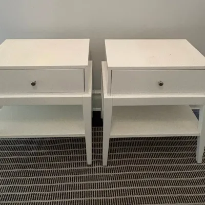 Sale Photo Thumbnail #64: Pair of modern white nightstands featuring a single drawer with a silver knob and a lower display shelf.