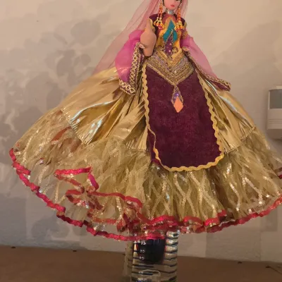 Sale Photo Thumbnail #50: Vintage souvenir doll in ornate traditional South Asian bridal attire featuring a layered metallic gold and maroon skirt with metallic trim and beaded headpiece.