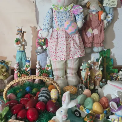 Sale Photo Thumbnail #22: A varied collection of Easter decor, including plush rabbit dolls, painted porcelain figurines, decorative eggs, and a woven basket.