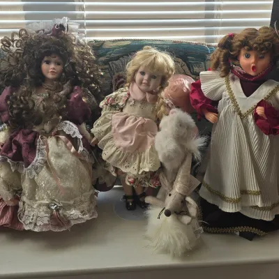 Sale Photo Thumbnail #107: Collection of vintage porcelain dolls in ornate Victorian-style dresses, accompanied by plush animal figures.