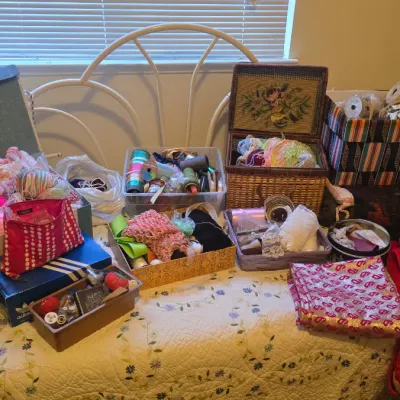 Sale Photo Thumbnail #78: Large collection of crafting and sewing supplies arranged on a bed, including yarn, ribbons, fabric, woven baskets, and storage boxes.