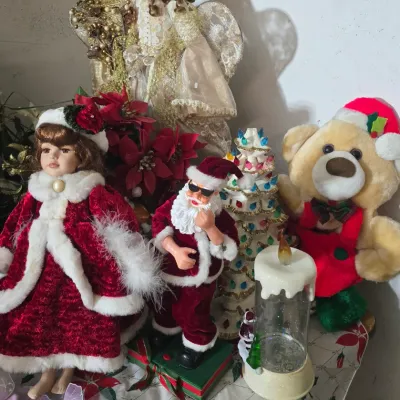 Sale Photo Thumbnail #39: Collection of holiday decorations including porcelain Christmas dolls, an animated Santa figure, a ceramic Christmas tree, and a teddy bear.