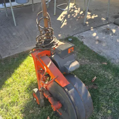 Sale Photo Thumbnail #136: Vintage heavy-duty electric drain snake auger machine in orange and grey metal, showing surface wear and age.
