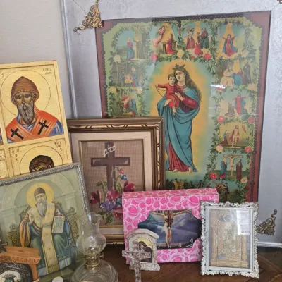 Sale Photo Thumbnail #119: Collection of Christian devotional art and religious items, including framed icons, a cross needlepoint, a small oil lamp, and a bottle labeled holy water.