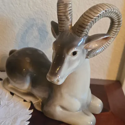 Sale Photo Thumbnail #47: Vintage Royal Copenhagen glazed porcelain figurine of a reclining ram or ibex, featuring detailed horns and a soft grey-and-white finish.