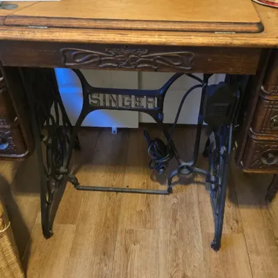 Sale Photo Thumbnail #74: Antique Singer treadle sewing machine wooden cabinet featuring cast iron legs, ornate drawer detailing, and an integrated pedal board.