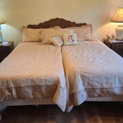 Sale Photo Thumbnail #4: Traditional wooden king bed frame with carved headboard, flanked by matching dark wood nightstands and ginger jar table lamps with patterned shades.