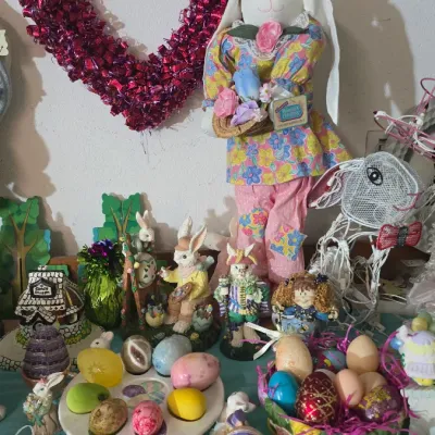 Sale Photo Thumbnail #21: Collection of spring and Easter decor, featuring a tall dressed rabbit doll, heart-shaped metallic wreath, decorative eggs, and assorted bunny figurines.