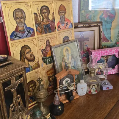 Sale Photo Thumbnail #120: Collection of Christian religious items featuring a multi-panel Greek Orthodox icon board, framed art, crucifixes, and oil lamps arranged on a wooden dresser.