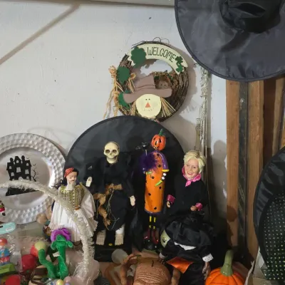 Sale Photo Thumbnail #19: Collection of Halloween decor items, including skeleton figures, a witch hat, a jack-o'-lantern, and novelty electronics.