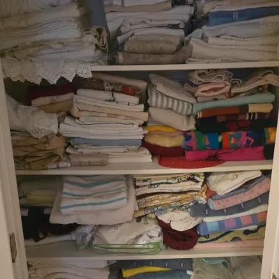 Sale Photo Thumbnail #71: A white linen closet packed with various folded household textiles, including bath towels, hand towels, bed sheets, and lace-trimmed linens.