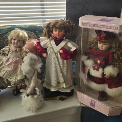 Sale Photo Thumbnail #108: Collection of holiday-themed porcelain and animated dolls, including a boxed Collectible Memories porcelain doll in a red velvet coat and an animated singing angel doll.