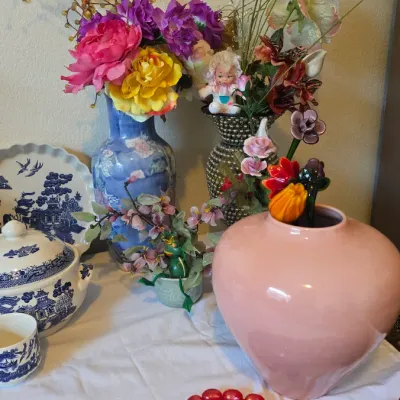 Sale Photo Thumbnail #5: Collection of decorative Asian ceramic vases, blue-and-white porcelain tableware, faux floral arrangements, and beaded necklaces displayed on a table.
