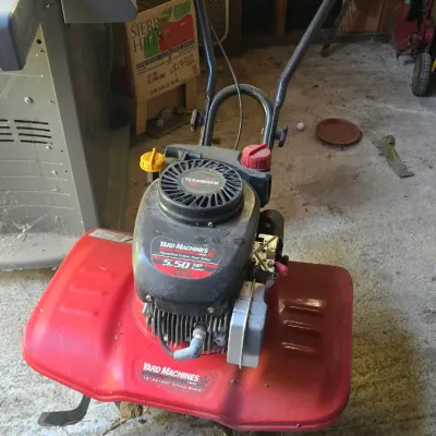 Sale Photo Thumbnail #89: Yard Machines front-tine garden tiller powered by a Tecumseh 5.50 HP engine. Features a red metal deck with adjustable tilling width settings.