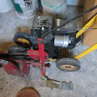 Sale Photo Thumbnail #87: McLane gas-powered lawn edger featuring a red and yellow frame with a small engine and rubber tires.
