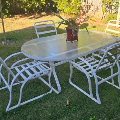 Sale Photo Thumbnail #93: White metal outdoor dining set featuring an oval glass-top table and four matching slatted armchairs.
