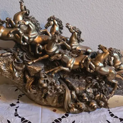 Sale Photo Thumbnail #45: Bronze-tone sculpture depicting eight galloping horses on a rocky base, flanked by a pair of glazed ceramic ram figurines.