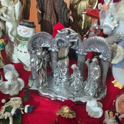 Sale Photo Thumbnail #30: Collection of holiday decorations, including a metallic silver nativity set, gold and white angel statues, a Mrs. Claus doll, and various vintage Christmas ornaments.