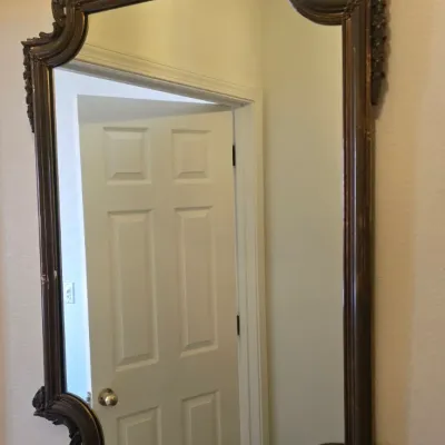 Sale Photo Thumbnail #126: Ornate vintage wall mirror featuring a dark carved wood frame with a decorative shell crest and scrolled edges.
