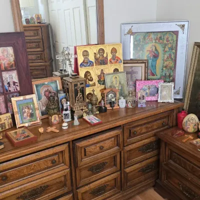 Sale Photo Thumbnail #123: Collection of Christian religious artwork, icons, and crucifixes displayed atop traditional wooden bedroom dressers.
