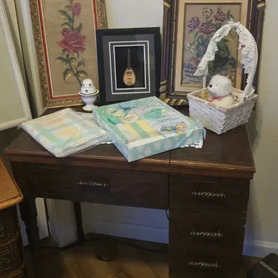 Sale Photo Thumbnail #73: Vintage dark wood sewing machine cabinet desk displayed with framed needlepoint artwork, framed miniature instrument art, and various decorative household items.