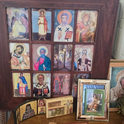 Sale Photo Thumbnail #122: Collection of Eastern Orthodox religious icons, framed icon collage, prayer books, and brass crosses displayed on a wooden surface.