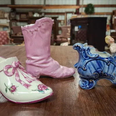 Trio of vintage ceramic shoe figurines and planters, including a floral-patterned pump, a pink high-button boot, and a ornate blue shoe...