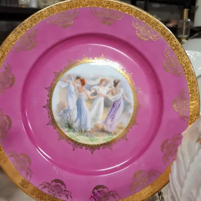 Antique porcelain cabinet plate featuring a hand-painted central vignette of dancing classical women, surrounded by a bright pink rim...