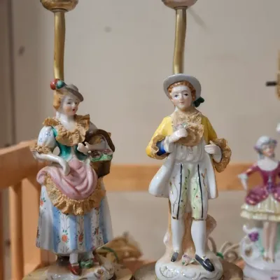 Pair of vintage porcelain figurine table lamps depicting a man and woman in 18th-century style attire, set on ornate brass bases.