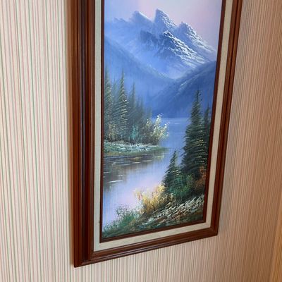 Sale Photo Thumbnail #124: Framed oil painting depicting a serene mountain landscape with a lake and evergreen trees.