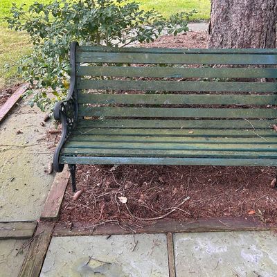 Sale Photo Thumbnail #55: Outdoor garden bench featuring dark green wooden slats and ornate black cast iron side frames.