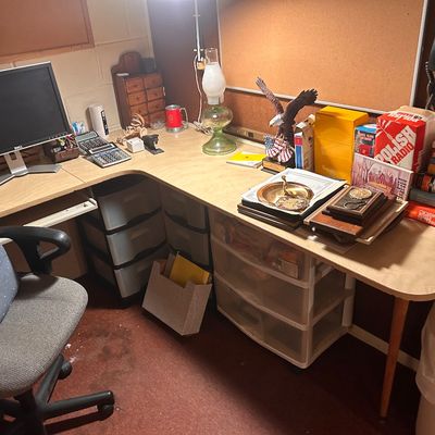 Sale Photo Thumbnail #66: L-shaped office desk setup featuring a Dell computer monitor, rolling office chair, oil lamp, eagle figurine, books, and various desktop office supplies.