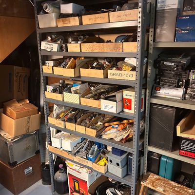 Sale Photo Thumbnail #4: Tall metal industrial shelving units filled with assorted hardware, lamp repair parts, electrical components, and vintage electronics.