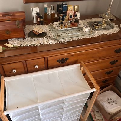 Sale Photo Thumbnail #85: Vintage wooden dresser displaying an array of perfume bottles, vanity trays, hand mirror, and small wooden trinket boxes.