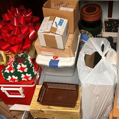Sale Photo Thumbnail #45: Assortment of household items, including a red Igloo cooler, holiday bows, crocheted slippers, storage boxes, and plastic baskets.
