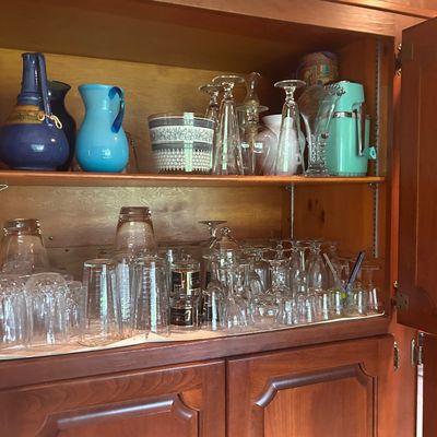 Sale Photo Thumbnail #13: Collection of glassware and ceramic pitchers, including vintage stemware, tumblers, and colorful art glass.