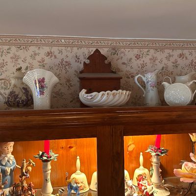 Sale Photo Thumbnail #109: A collection of vintage porcelain pitchforks, floral vases, decorative bells, figurines, and a wooden hutch display.